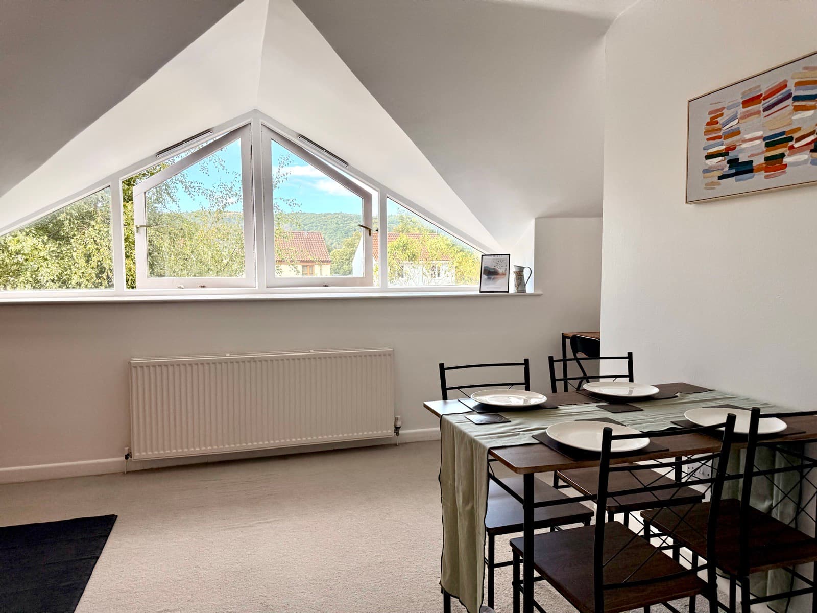 Cheddar — dining table beneath a triangular window with hills beyond
